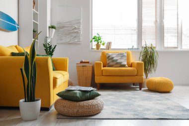 Sörf tahtası, sarı kanepesi ve koltuğu olan bir oturma odası.