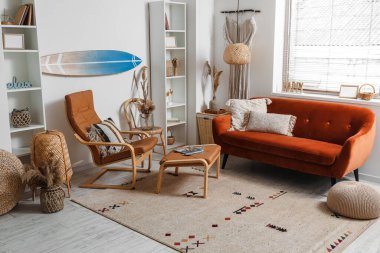 Sörf tahtası, kahverengi kanepesi ve koltuğu olan bir oturma odası.