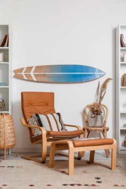 Sörf tahtası ve kahverengi koltuklu bir oturma odası.