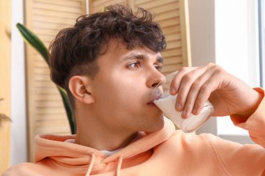 Evde süt içen genç adam, yakın plan.