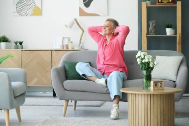 Mutlu olgun kadın evde koltukta oturan