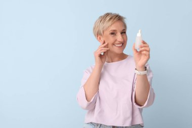 Mavi arka planda serumu olan olgun bir kadın.