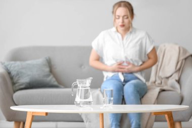 Odadaki masada çözünür tabletli sürahi ve bardak su, yakın plan.