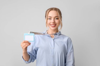 Gri arkaplanda boş rozetli genç bir kadın.