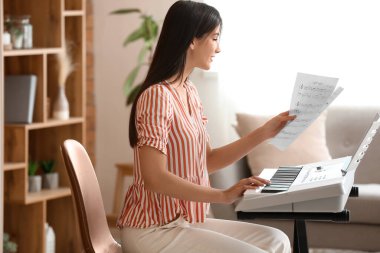 Genç bayan müzisyen evde sentezleyici çalıyor.