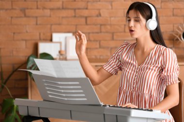 Genç bayan müzisyen evde sentezleyici çalıyor.