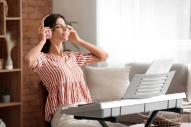 Genç bayan müzisyen evde sentezleyici çalıyor.