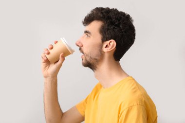 Genç esmer adam açık arkaplanda bir fincan kahveyle