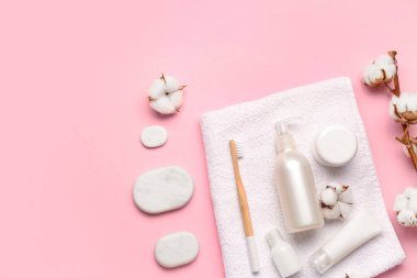 Kozmetik ürünleri, spa taşları ve pembe arka planda pamuk dalı