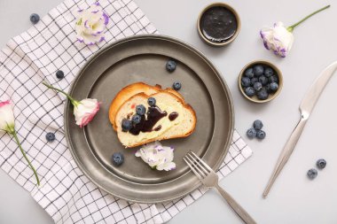 Lezzetli reçelli tost tabağı, gri arka planda yabanmersini ve çiçekler.