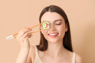 Bej arka planda suşi yuvarlayan genç bir kadın, yakın plan.