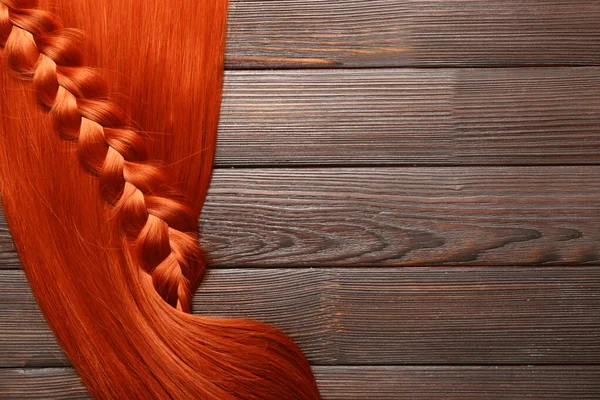 Rude Włosy Warkoczem Drewnianym Tle Zbliżenie — Zdjęcie stockowe