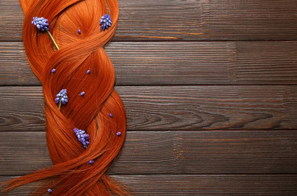 木の背景にムスカリの花を持つ美しい生姜の髪 クローズアップ — ストック写真