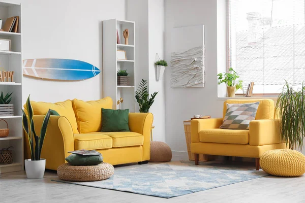 stock image Interior of light living room with surfboard, yellow sofa and armchair