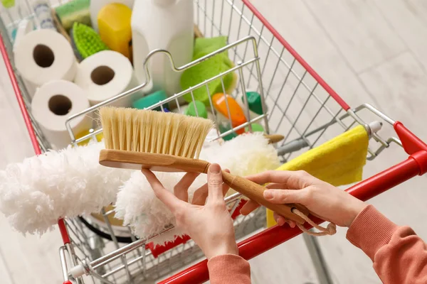 stock image Woman with shopping cart full of cleaning supplies on wooden floor