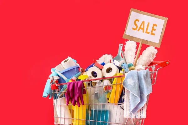 赤い背景に単語Saleと掃除用品でいっぱいのショッピングカート — ストック写真
