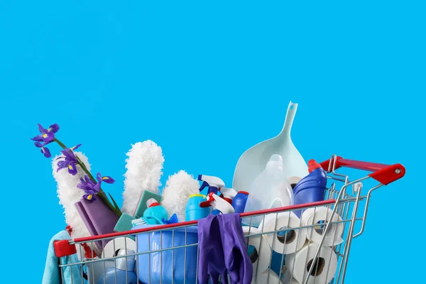 Carrinho Compras Cheio Suprimentos Limpeza Flores Roxas Fundo Azul — Fotografia de Stock