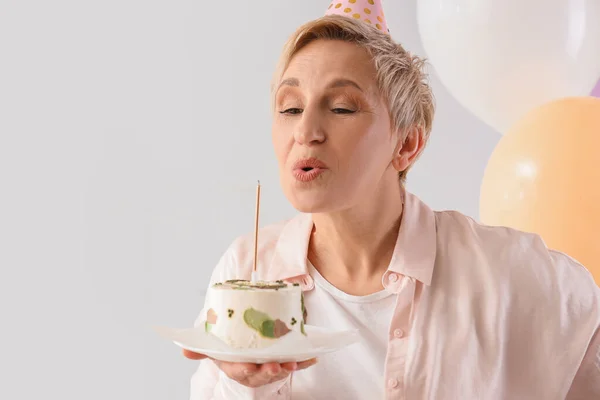 Dojrzałe Kobieta Tort Urodzinowy Podejmowania Życzenia Lekkim Tle Zbliżenie — Zdjęcie stockowe