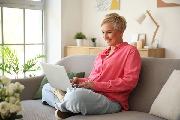 stock image Mature woman using laptop on sofa at home