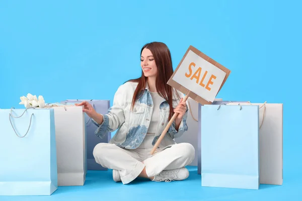 Young Woman Sale Sign Shopping Bags Sitting Blue Background — Stock Photo, Image