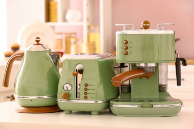 Elektrik ısıtıcısı, tost makinesi ve kahve makinesi mutfaktaki beyaz masada.