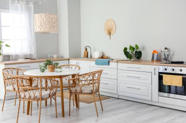 Beyaz tezgahları, elektrikli fırını ve yemek masası olan açık mutfak.