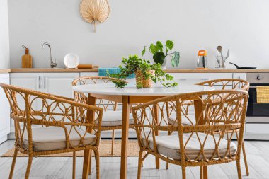 Mutfağın içinde yemek masası ve beyaz tezgahlar var.