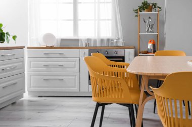 Beyaz tezgahlı ve yemek masalı aydınlık mutfağın içi.