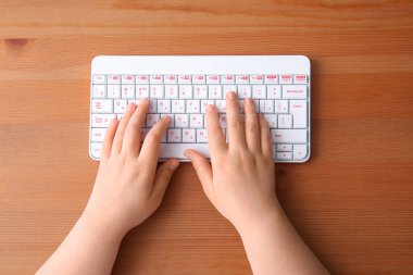 Tahta masadaki bilgisayar klavyesini kullanan kadın programcı