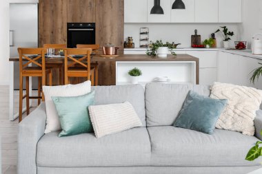 Açık uzay mutfağının içi rahat gri kanepe ve ada masasıyla dolu.