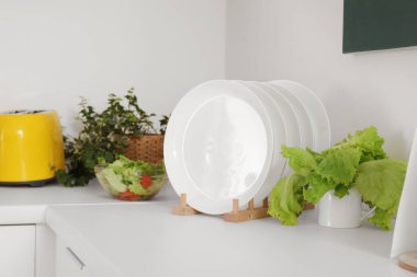 Tabak rafı, marul ve tost makinesi olan beyaz mutfak tezgahı.