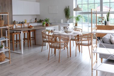 Açık uzay mutfağının içinde yemek masası, ada ve büyük pencere var.