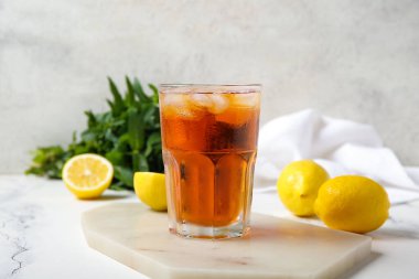 Beyaz arka planda bir bardak buzlu çay ve limonlu tahta.