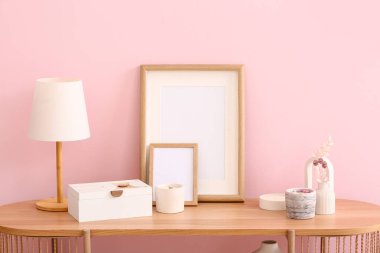 Mumlu tutucular, boş çerçeveler, lamba ve dekor odada pembe duvarın yanında.