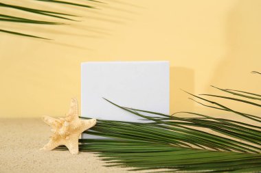 Palmiye yapraklarıyla dekoratif sıva podyumu ve sarı arka planda deniz yıldızı.