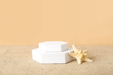 Dekoratif sıva podyumları kumların üzerinde soluk turuncu arka planda deniz yıldızlarıyla