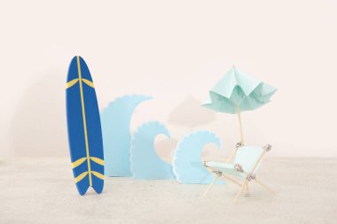 Mini sörf tahtası, minyatür şezlonga ve beyaz masada kağıt dalgalara sahip yaratıcı kompozisyon