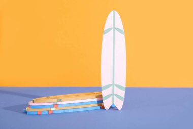 Mavi masada turuncu arka planda bir sürü renkli sörf tahtası var.