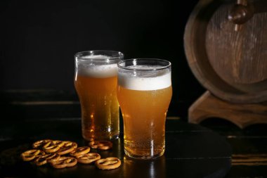 Koyu arkaplanda krakerli soğuk bira bardakları.