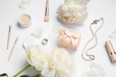 Beyaz arka planda hediye kutusu, kadın aksesuarları, kozmetik ürünleri ve şakayık çiçekleri olan kompozisyon