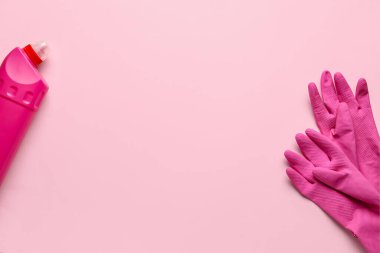 Bir çift koruyucu lastik eldiven ve pembe arka planda bir şişe deterjan.