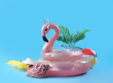 Mavi arka planda şişme halkaları, bitki ve plaj aksesuarları olan yaratıcı bir kompozisyon. Yaz tatili kavramı