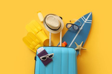 Sörf tahtası, pasaport ve sarı arka planda plaj aksesuarları. Yaz tatili kavramı