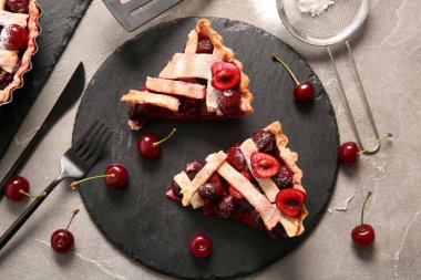Gri arka planda lezzetli vişneli turta parçaları olan tahta