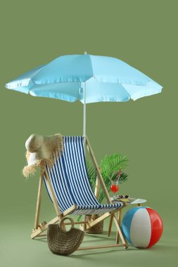 Güverte sandalyesi, şemsiyesi, plaj aksesuarları ve yeşil arka plandaki taburede kokteyl. Seyahat kavramı