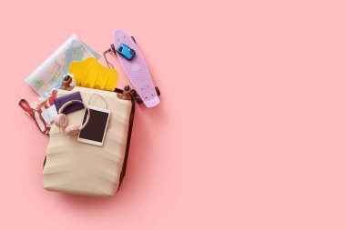 Pasaportlu bavul, kulaklık, harita ve pembe arka planda plaj aksesuarları. Seyahat kavramı