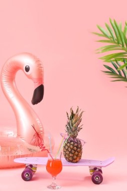 Şişme yüzük, kokteyl, kaykay ve pembe arka planda ananas. Seyahat kavramı