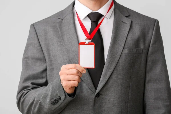 Stock image Young businessman with blank badge on light background, closeup