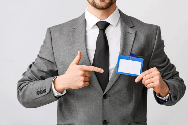 Young Businessman Pointing Blank Badge Light Background — Stock Photo, Image