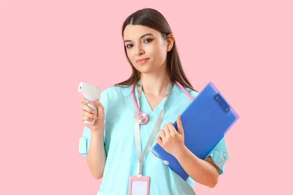 Ženská Lékařská Stážistka Infračerveným Teploměrem Schránkou Růžovém Pozadí — Stock fotografie